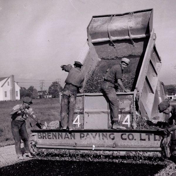 1950s Paving crew shovels the last of the asphalt from the dump box into the paver. (Source: Miller Paving)