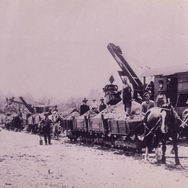 Two old loaders with Franceschini logo loading horse-drawn wagons on a rail track - 1920s